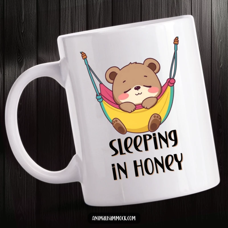 Funny Bear Cub Mug showing a smiling cub blissfully fast asleep in a colorful hammock, embodying peaceful slumber and adorable charm.